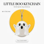 Illustration: the little boo ghost keychain hanging from its cord in front of a yellow circle
