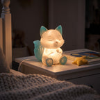 Illustration: the fox night light glowing at night in a child's bedroom beside a picture book