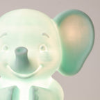 Illustration: close-up of the elephant night light's face, trunk and ear glowing mint